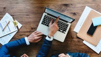 Business person pointing at laptop screen.